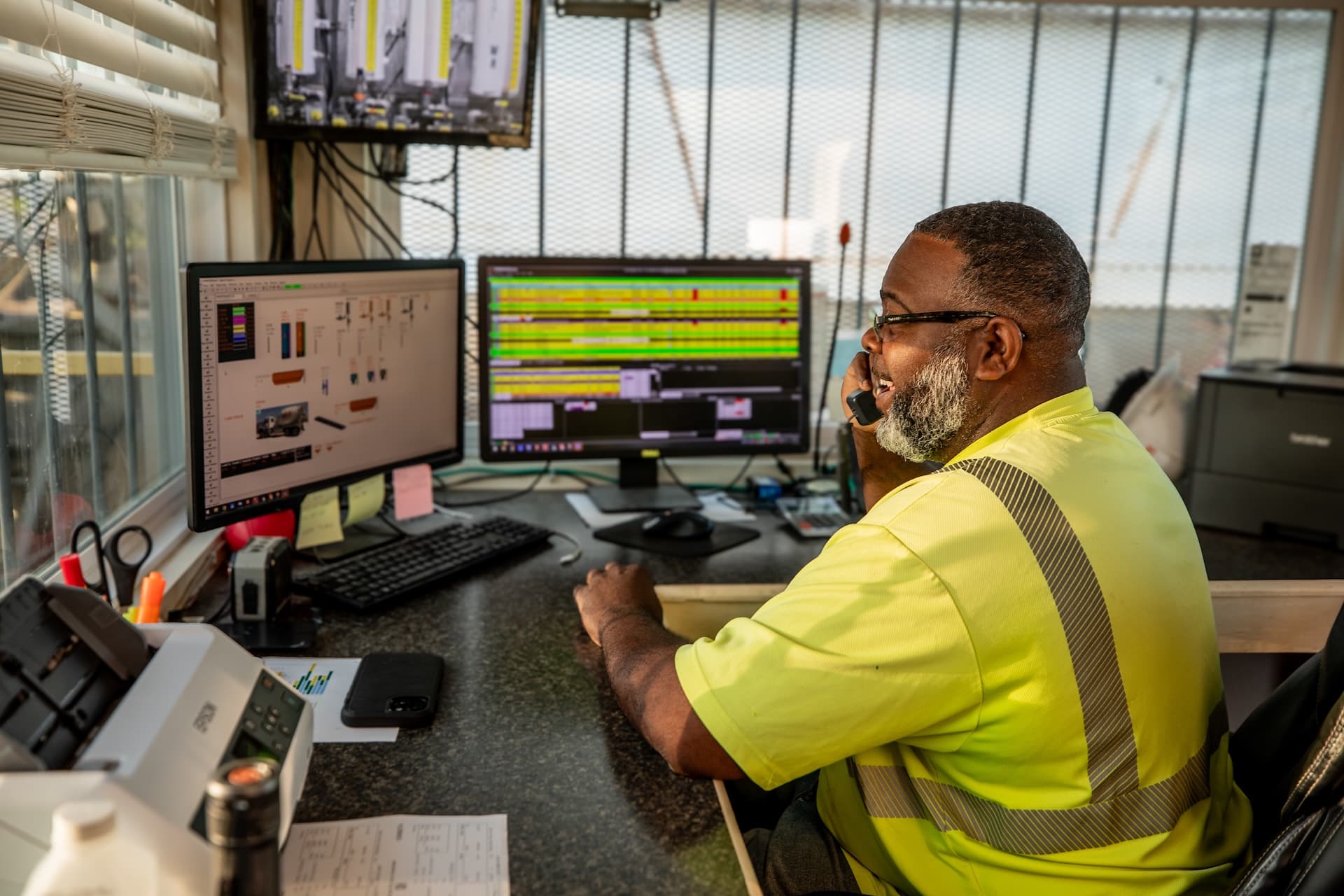 Plant manager at his desk looking at the screens and talking on the phone
