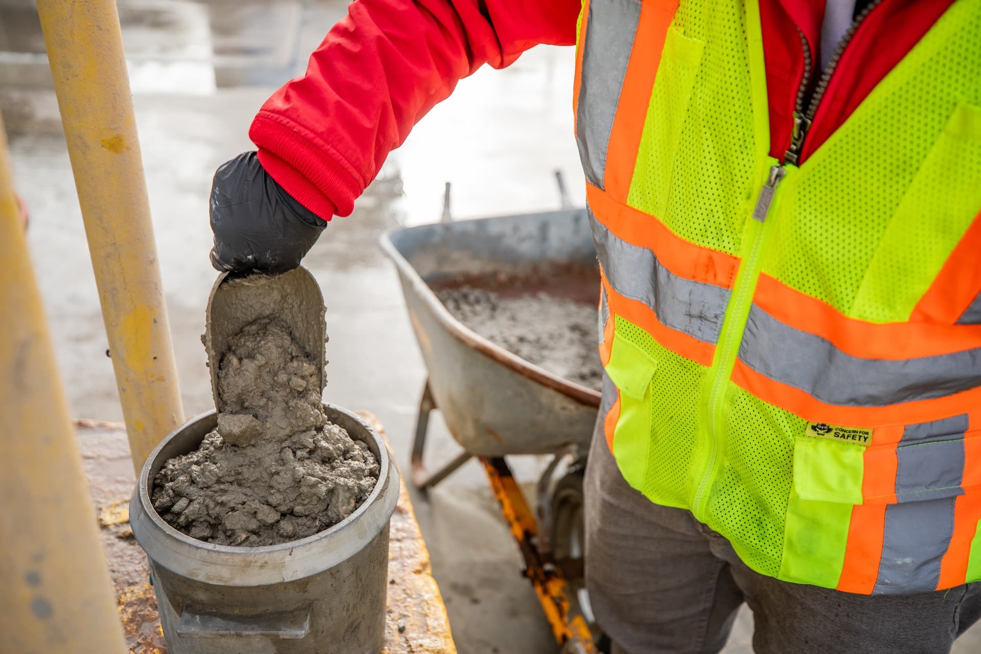 A Lauren Concrete Quality Control Technician pouring concrete into a cylinder for testing
