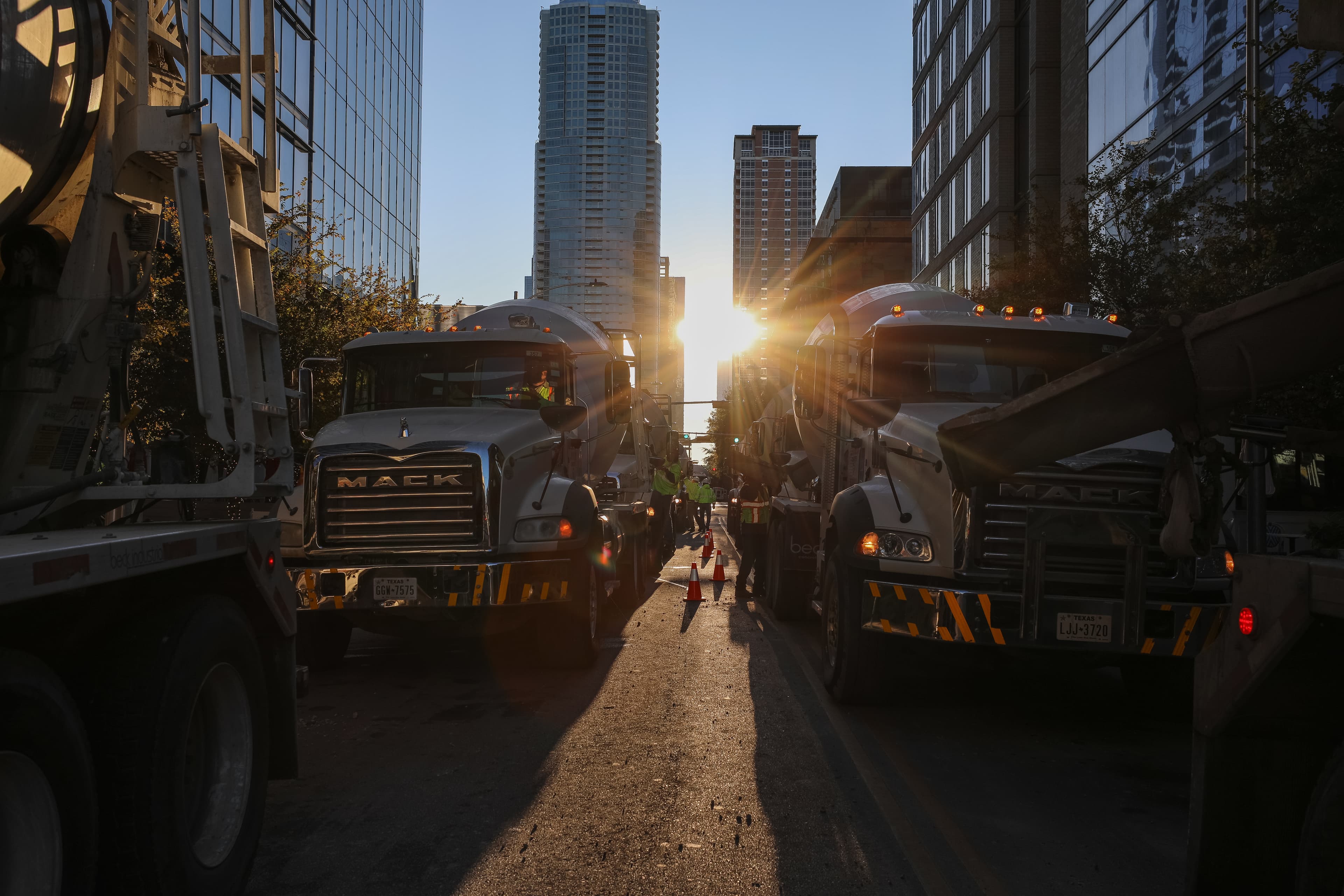 Trucks lined up at Block 185 project with the sun shining through the downtown buildings