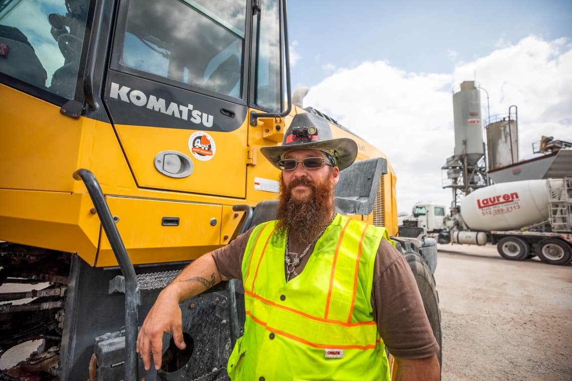 Loader operator standing next to his loader at the concrete plant