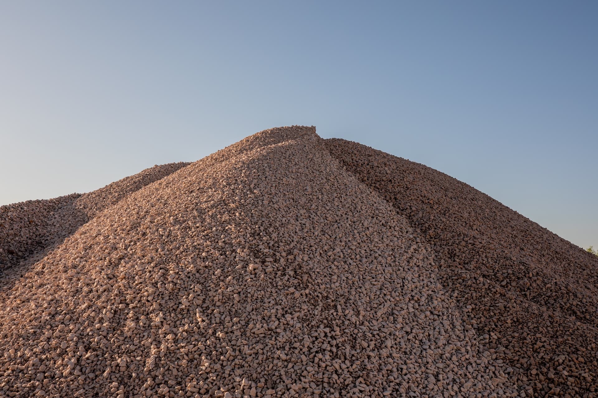 A pile of rock with a blue sky in the background and the sun shining on one side.