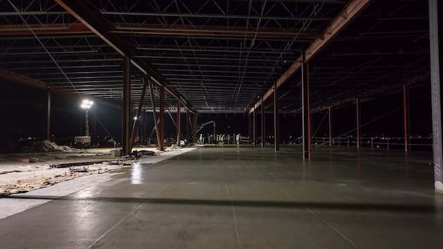 freshly poured concrete smoothed out with a finishing crew and pump in the background_small
